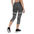 Load image into Gallery viewer, Elevate your wardrobe with these Elevated Essence Capris, the perfect addition to your athleisure collection. These capris feature a sleek and stylish design with white horizontal lines on a dark grey base, creating a striking yet versatile look that can be dressed up or down. The four-way stretch fabric ensures a comfortable and flexible fit, while the high-rise waistband offers support and coverage.